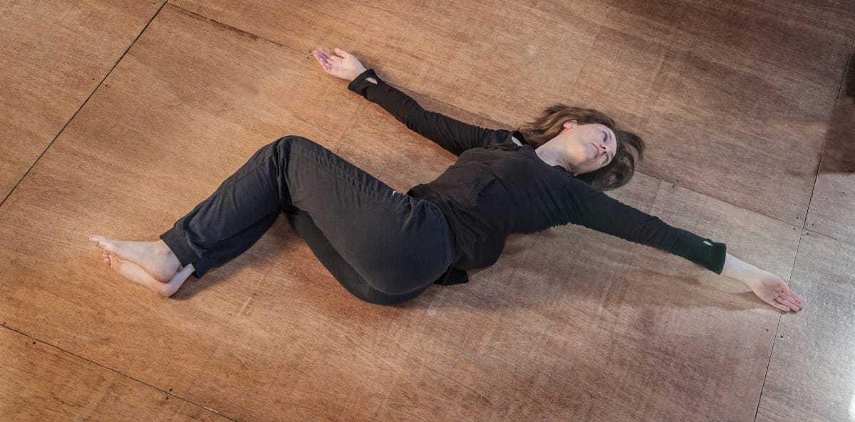 Woman on floor hands streched. Legs bent, one on the other.